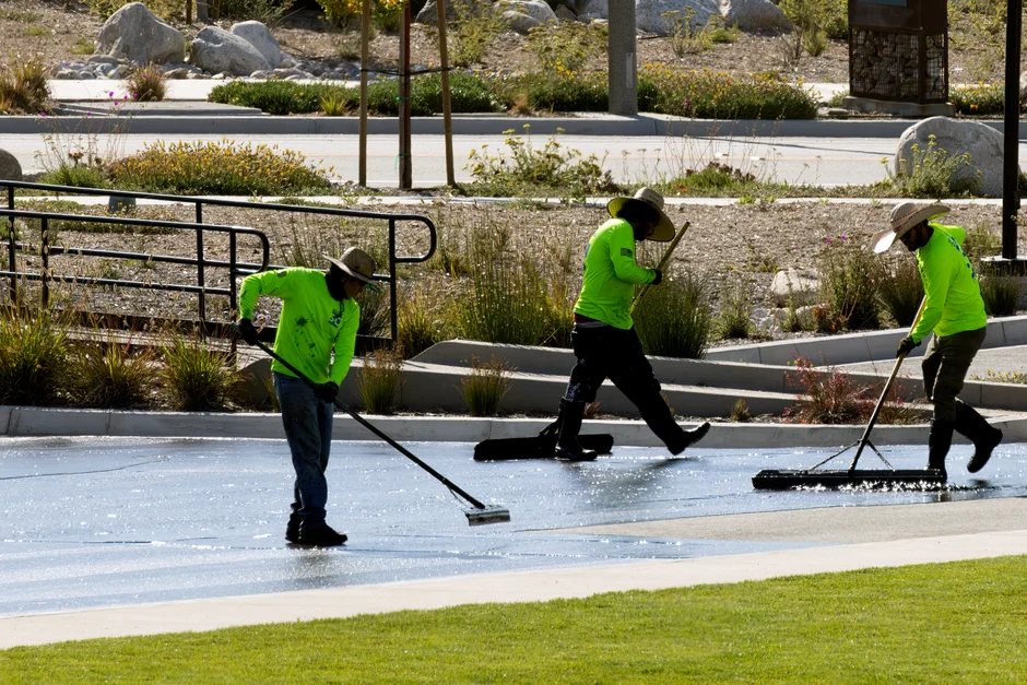 our-story Two workers cleaning windows on a glass building facade using a lift platform, enhancing building aesthetics.